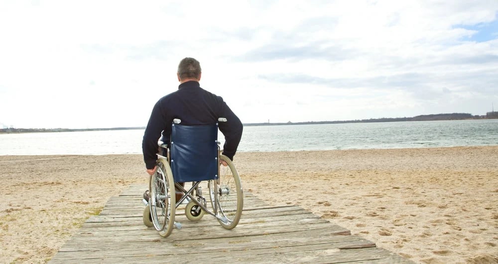 Usuario en silla de ruedas contemplando el mar.