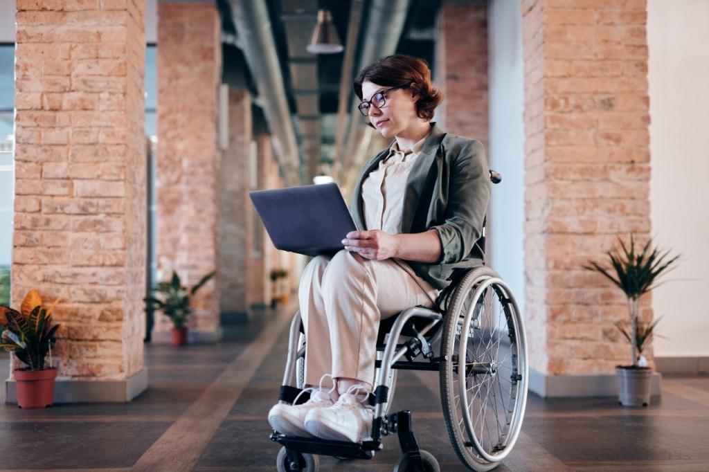 Mujer usuaria de silla de ruedas trabajando en su laptop.