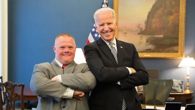 Joe Biden espalda con espalda con un joven con síndrome de Down.