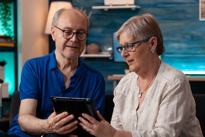 Dos adultos mayores utilizando una tablet.