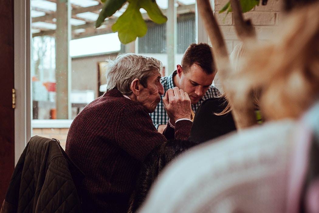 Adulto mayor en una cafetería conversando con un joven.