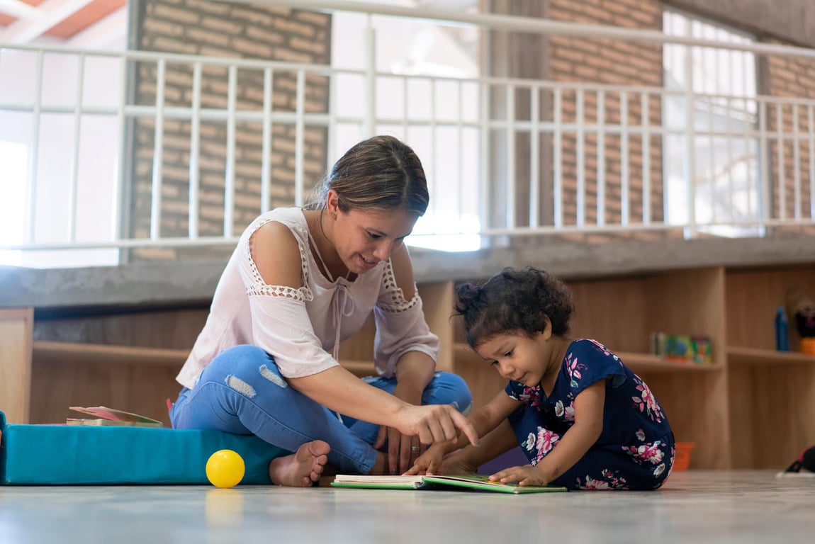 Maestra de kinder jugando con un alumno menor.