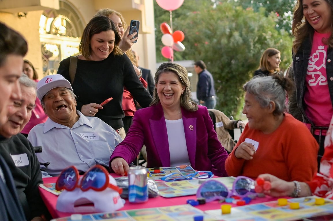 Martha Herrera riendo a carcajadas con adultos mayores.