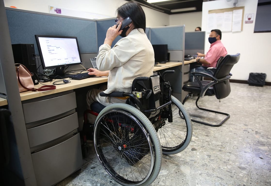 Usuaria de silla de ruedas atendiendo un teléfono en oficina.