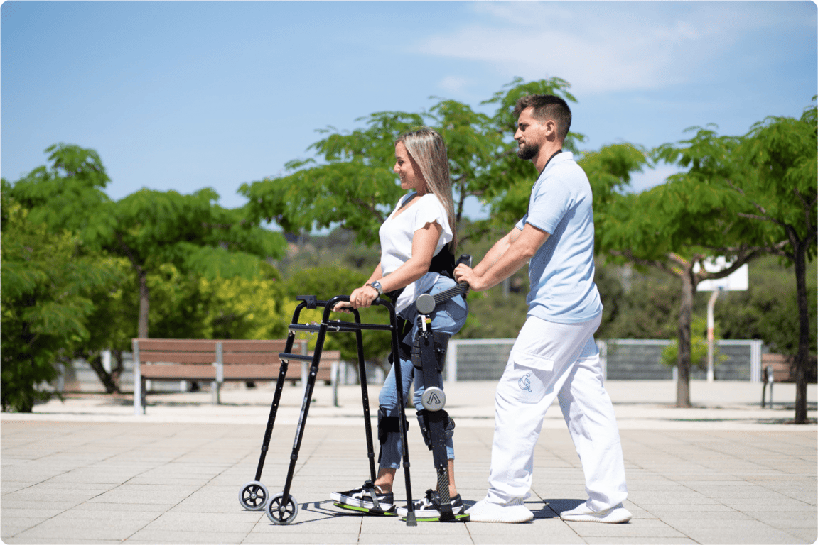Mujer de edad mediana utilizando un exoesqueleto apoyada por una andadera.
