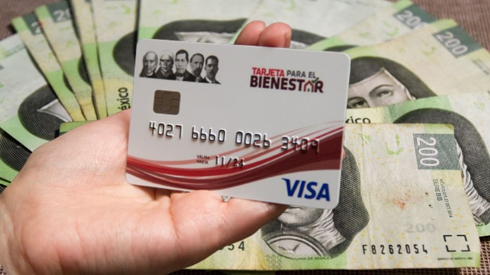 Persona sosteniendo su tarjeta de pensión del Bienestar y dinero en efectivo.