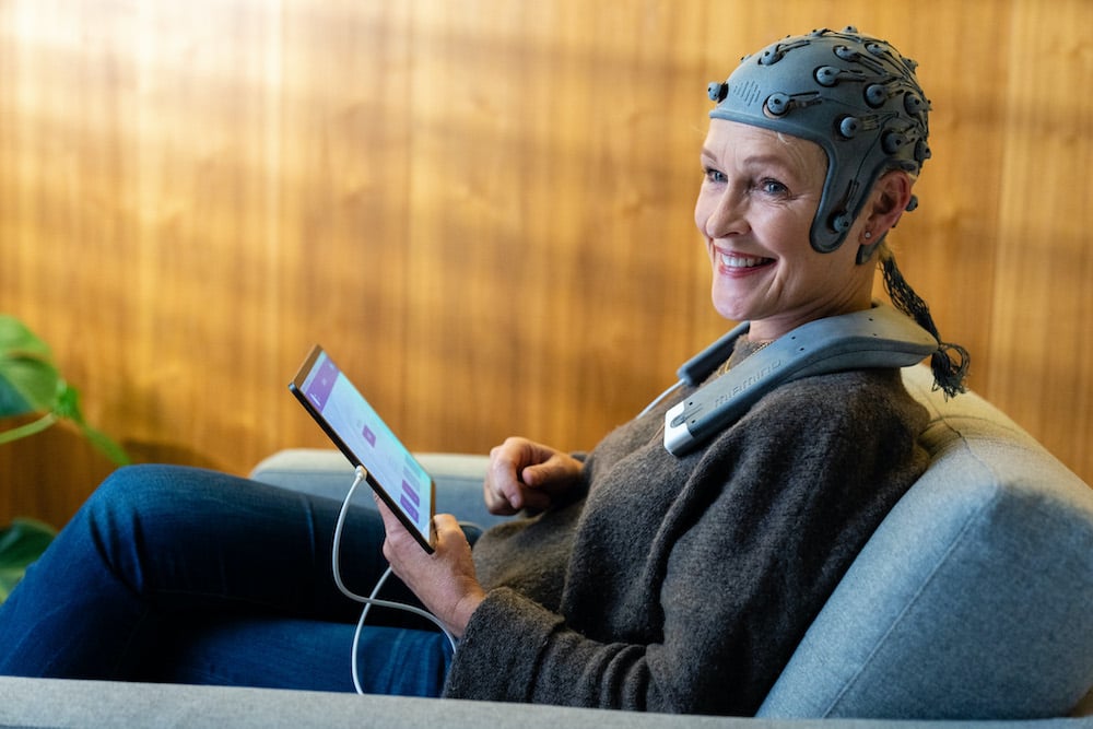 Persona con alzhéimer con nodos electrónicos conectados a su cabeza y monitoreados mediante una tableta.