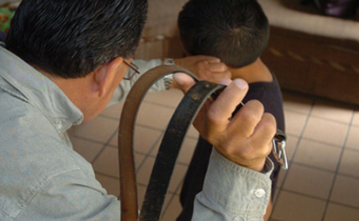 Adulto con un cinturón a punto de golpear a un menor de edad.