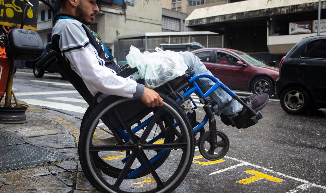Usuario en silla de ruedas cruzando una calle con automóviles