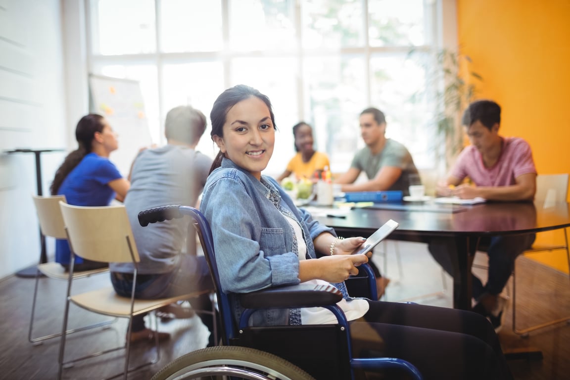 Usuario de silla de ruedas sonríe en una reunión laboral