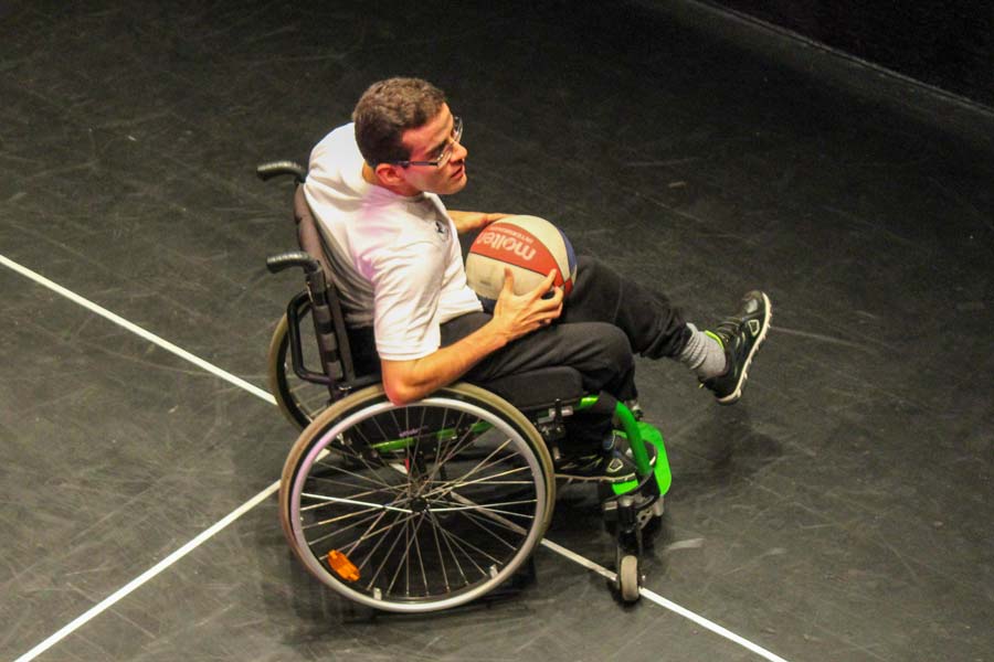 Usuario en silla de ruedas jugando básquetbol adaptado