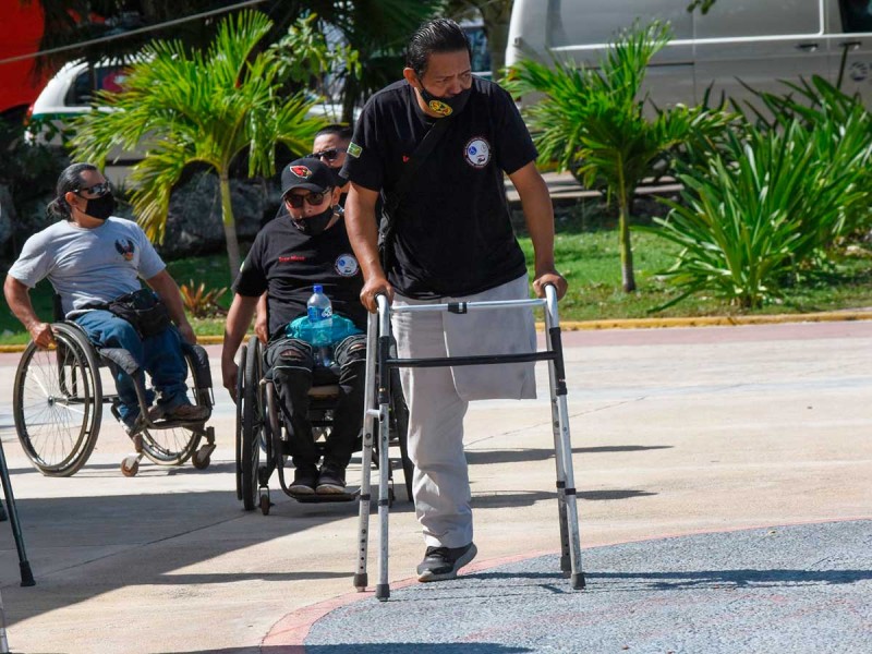 Calle con tres personas con discapacidad motriz