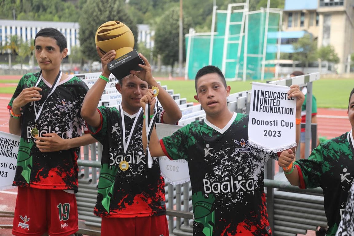 El equipo de futbol de Gladiadores Especiales sosteniendo su trofeo.