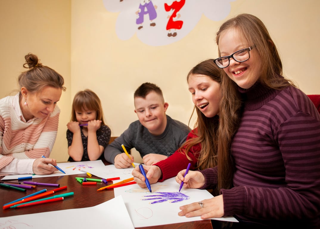 Grupo de niños y niñas con síndrome de Down tomando clases junto a su maestra.
