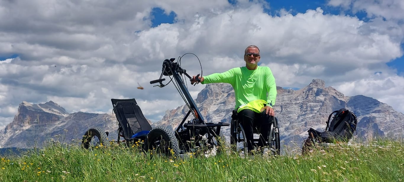 Fotografía del Manul 4x4 Handquad junto a una persona con discapacidad en la cima de una montaña.