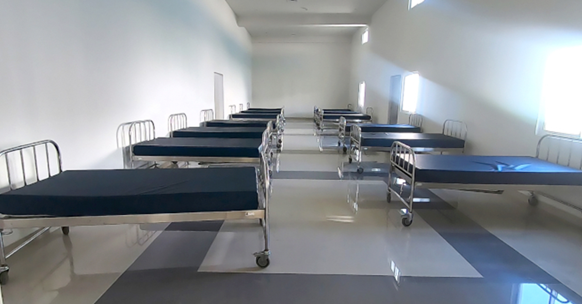 Pabellón de un hospital psiquiátrico con una línea de camas vacías.