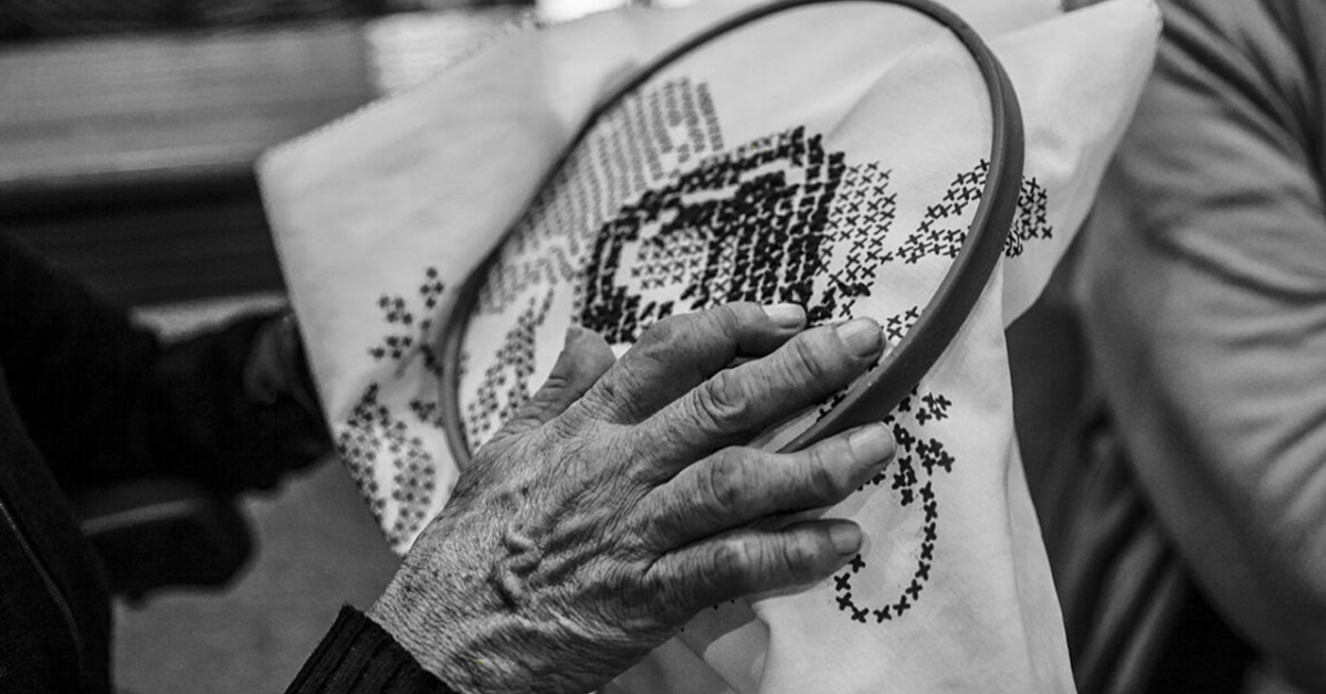 Fotografía de la mano arrugada de una mujer tejiendo.