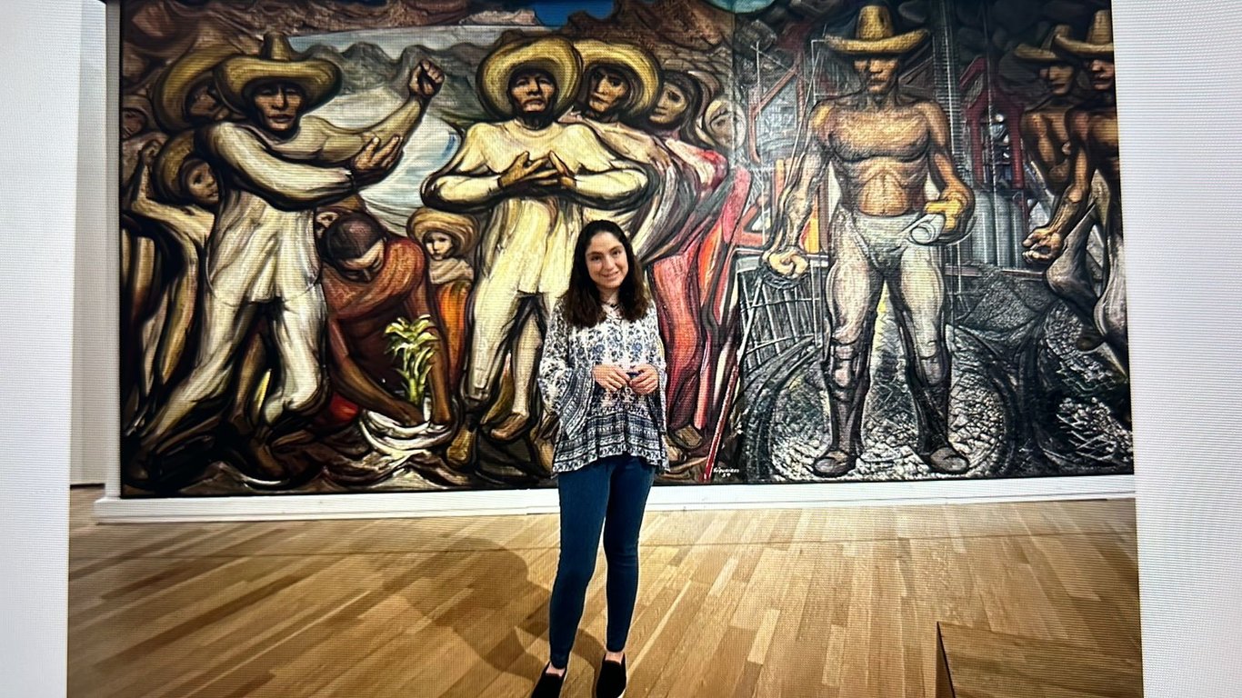 Fotografía de Ana Paula posando frente a una pintura.