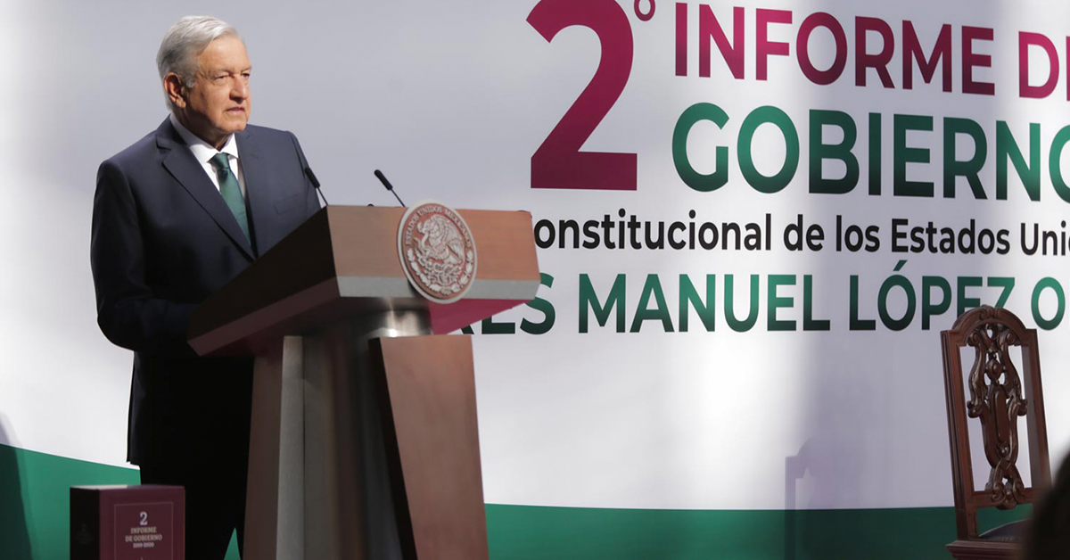 Fotografía de Andres Manuel López Obrador parado frente al estrado mientras da el segundo informe de gobierno, detrás de el en letras grandes el título segundo informe de gobierno.