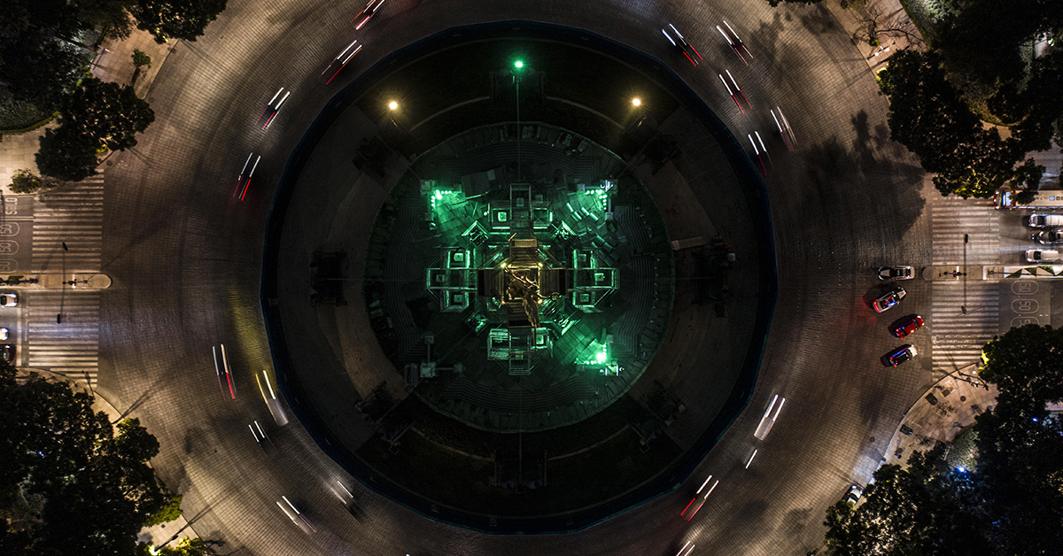 Fotografía aerea del angel de la independencia con tres luces verdes a su alrededor.