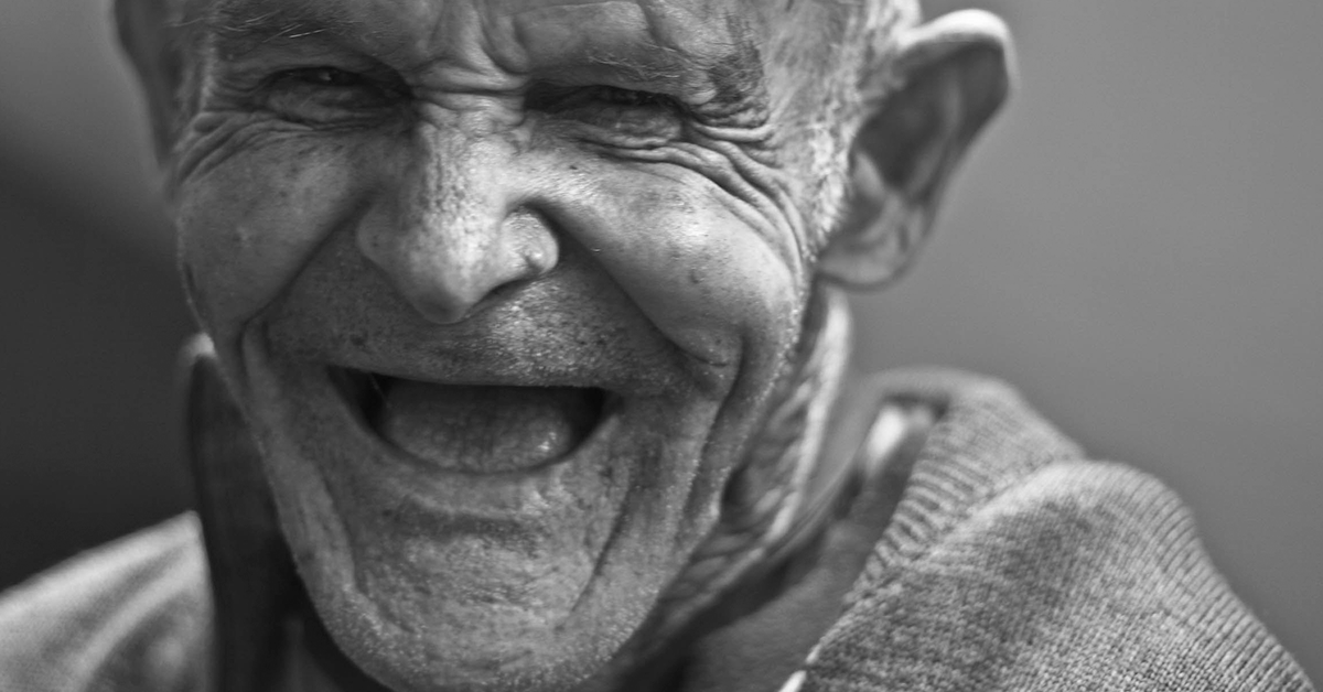 Fotografía en blanco y negro de un adulto mayor sonriendo.