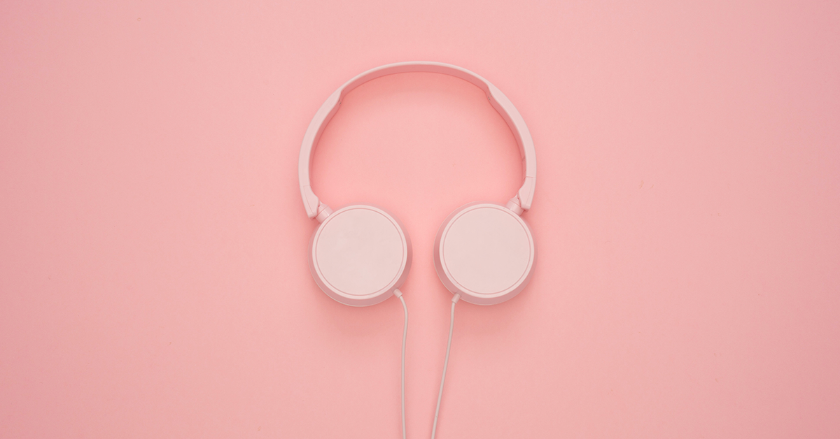 Fotografía de unos audífonos color rosa sobre una mesa.