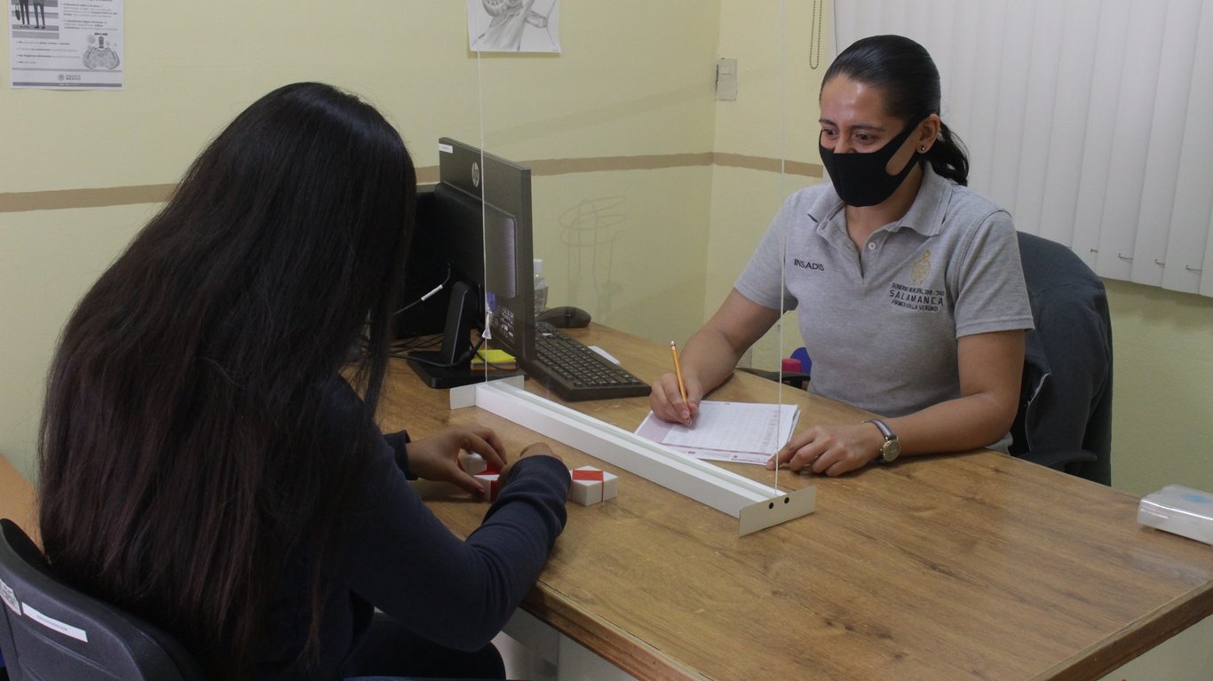 Fotografía del personal del Instituto Salmantino atendiendo a una persona con las debidas medidas de seguridad sanitaria.