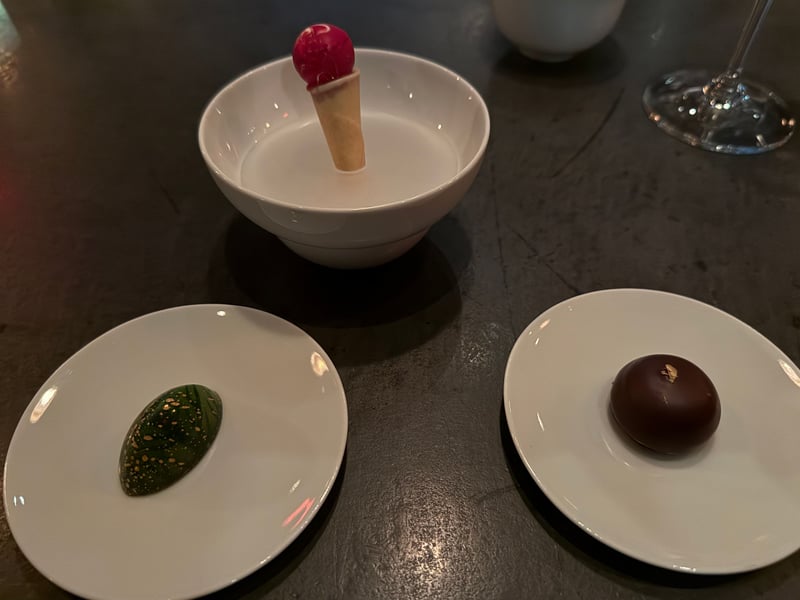 コーンに載せた赤い球、金を散らした緑のボンボン、黒いチョコレート