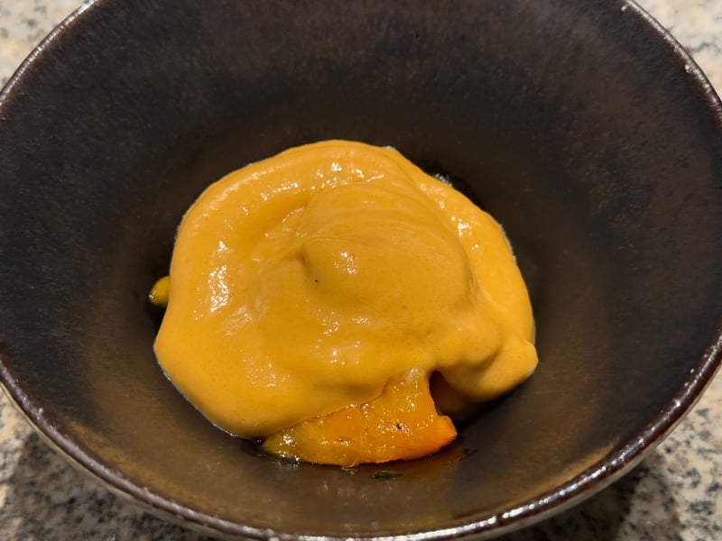 黒い鉢の代白柿に、とろりとしたソースをかけたもの