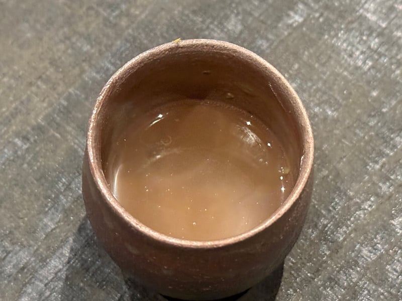 焼締めの器に半分ほど注がれた明石鯛のアラのスープ