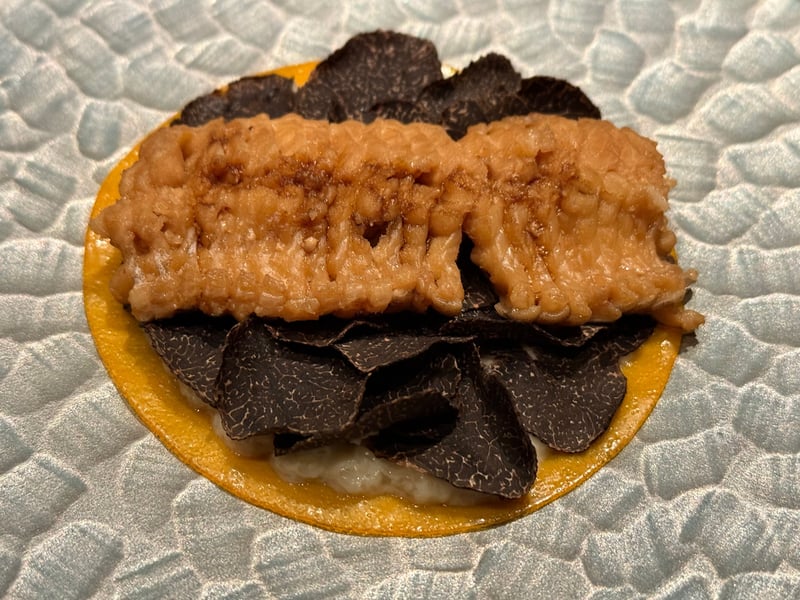 薄焼き卵の丸い生地に黒トリュフを敷き詰め、その上に明石の伝助穴子をのせた一皿