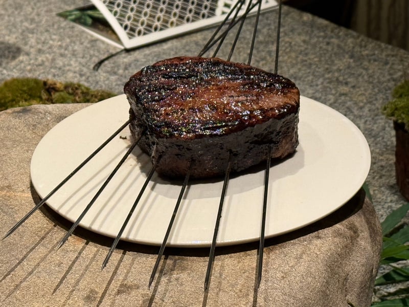 金串を何本も打ったまま皿にのせた、表面を焼いた近江牛の塊