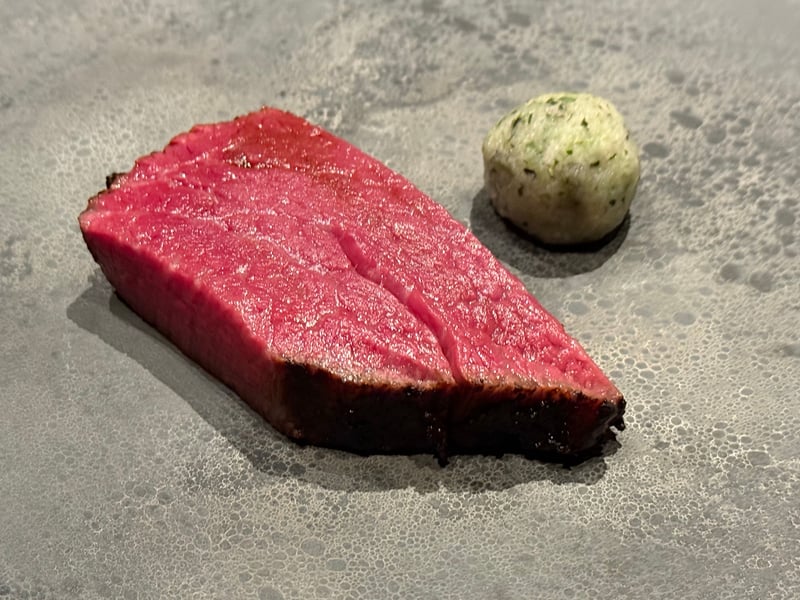 泡立てたソースの上に切り分けた近江牛と、緑の衣をまとった大根のボール