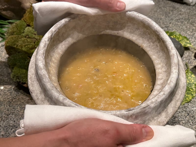 布で押さえた土鍋の蓋を開けたところ、蟹のおじやが炊けている