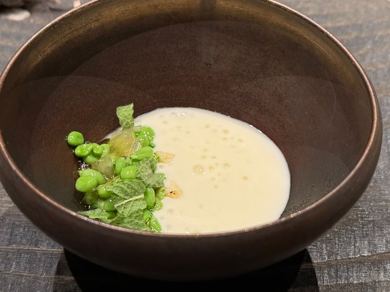 黒い椀に流したチーズのクリームと、ミントを重ねたグリーンピース