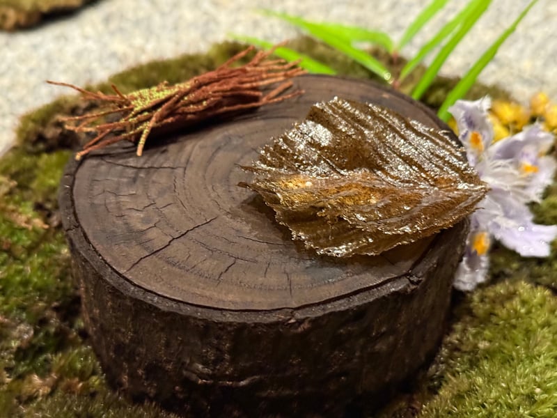 苔を敷いた切り株の上に置いた、葉の形の菓子と枝を束ねたクッキー