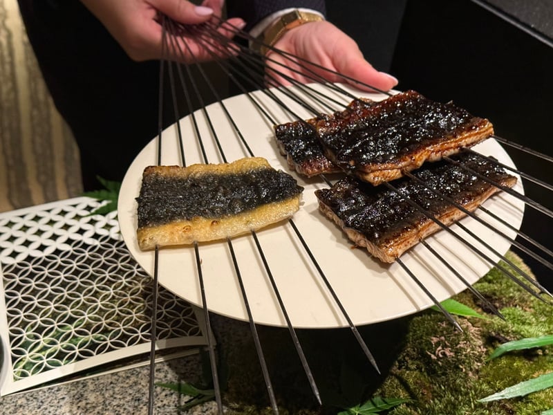 串を打って焼いた天然うなぎを、丸い台にのせて卓に見せているところ