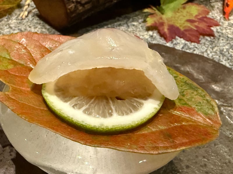 紅葉した葉とレモンの輪切りにのせた、昆布出汁で締めた明石の鯛