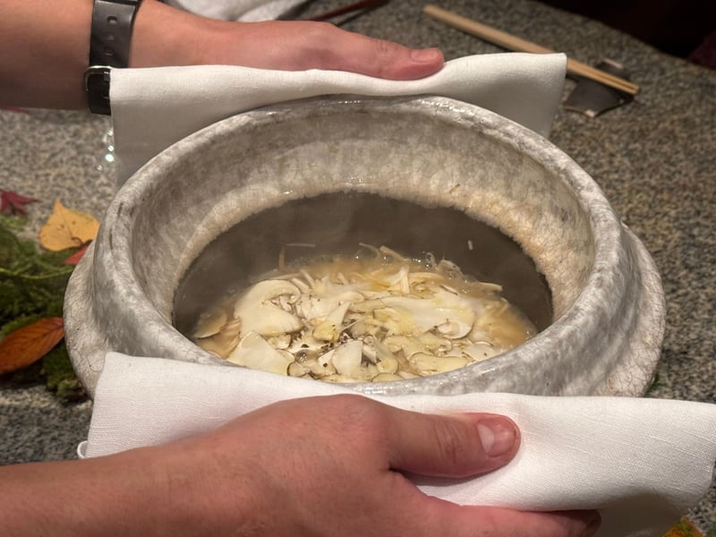 布で挟んで運ばれてきた土鍋の中、出汁に浮かぶ松茸のスライス