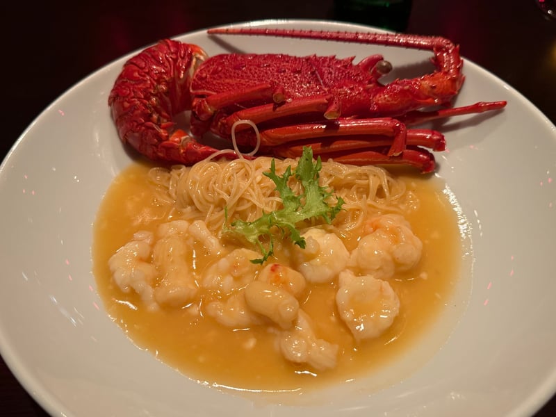殻ごとの伊勢海老を皿の奥に置き、手前に細い麺と海老の身をチーズのソースで煮込んで