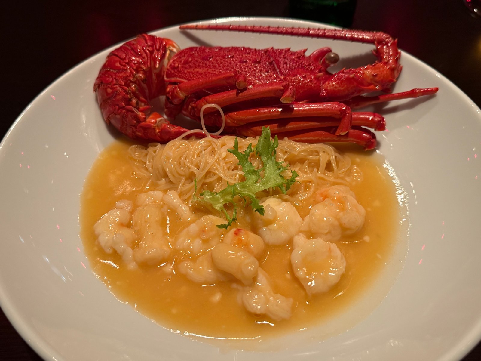 殻ごとの伊勢海老を皿の奥に置き、手前に細い麺と海老の身をチーズのソースで煮込んで