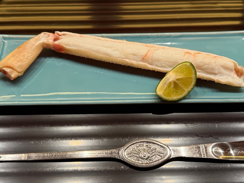 青磁の長皿に蒸した脚を一本、酢橘を添えて。手前に蟹の意匠の匙