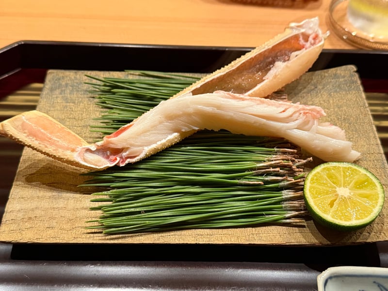 折敷の上、松葉に殻を開いた脚を並べて、酢橘を半分添える