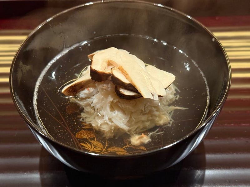 黒い椀に蟹のしんじょう。薄切りの松茸を重ね、澄んだ出汁を張る