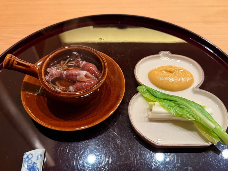 把手付きの飴釉の器に、出汁を張ったホタルイカの釜揚げ。瓢箪形の皿にうるいと酢味噌