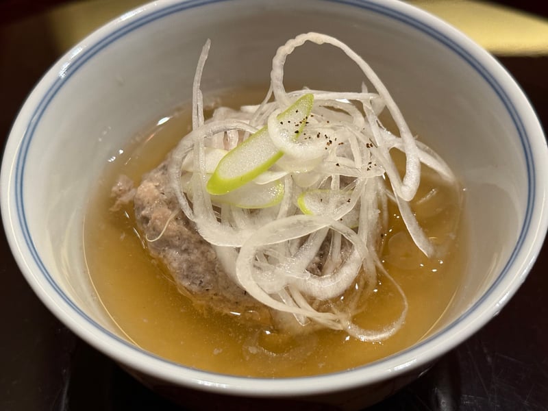 白い碗の出汁に、いわしのつみれと薄く切った長葱