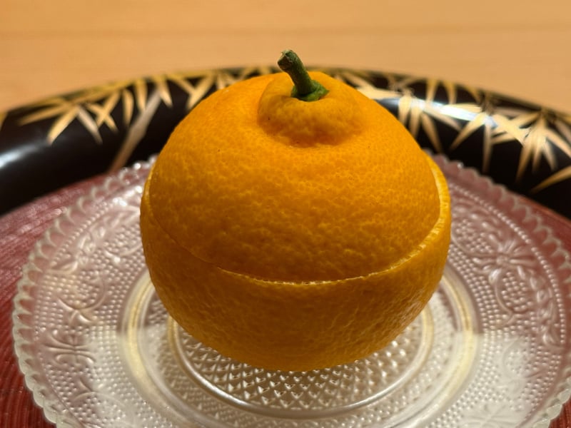 ガラスの皿に、蓋を切った三宝柑がまるごと1つ