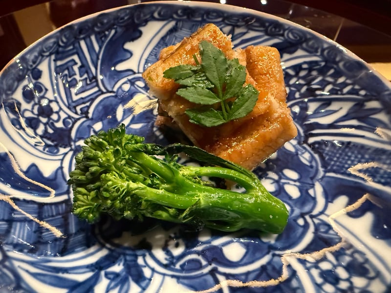 染付の皿にのせた天然鰻の蒲焼き二切れとスティックブロッコリー