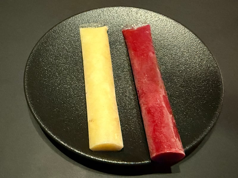 黒い皿に、白と赤のアイスキャンディー