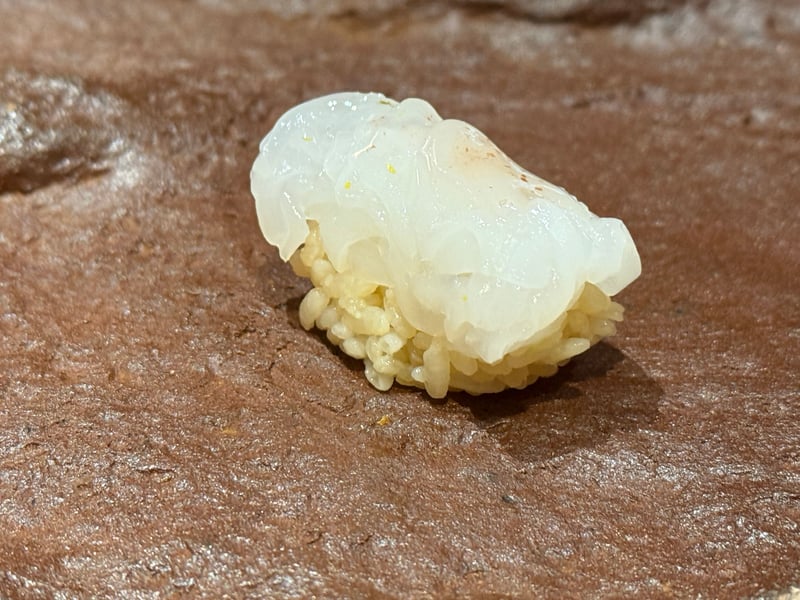 茶色い石の台にのった、白く厚いアオリイカの握り。